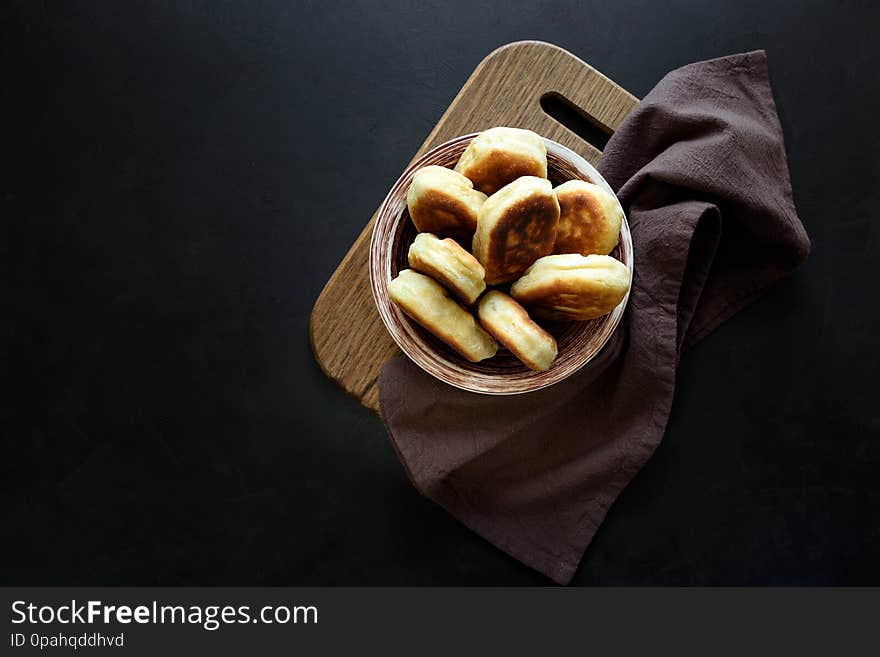 Fried patties or pies filled green onion and eggs on dark wooden background. Pirozhki Russian tradition food.