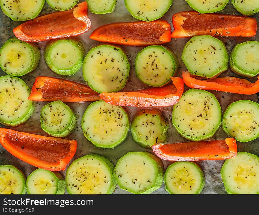 Vegetables with spices and herbs in oil on the baking sheet. Vegetarian dish. The view from the top. Flat lay