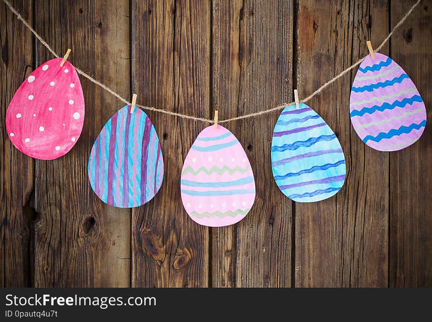 Paper Easter painted eggs painted hang on clothespins on  background old wooden wall