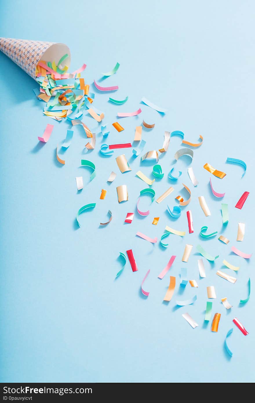 Birthday hat with confetti on blue paper background