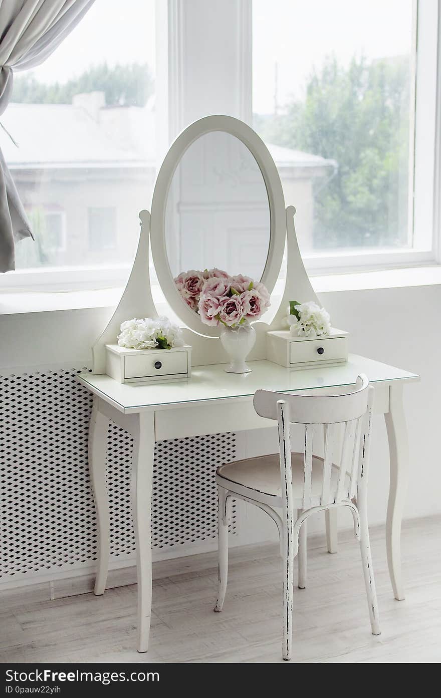 A beautiful white mirror on the table. Elegant bright interior. Close-up.