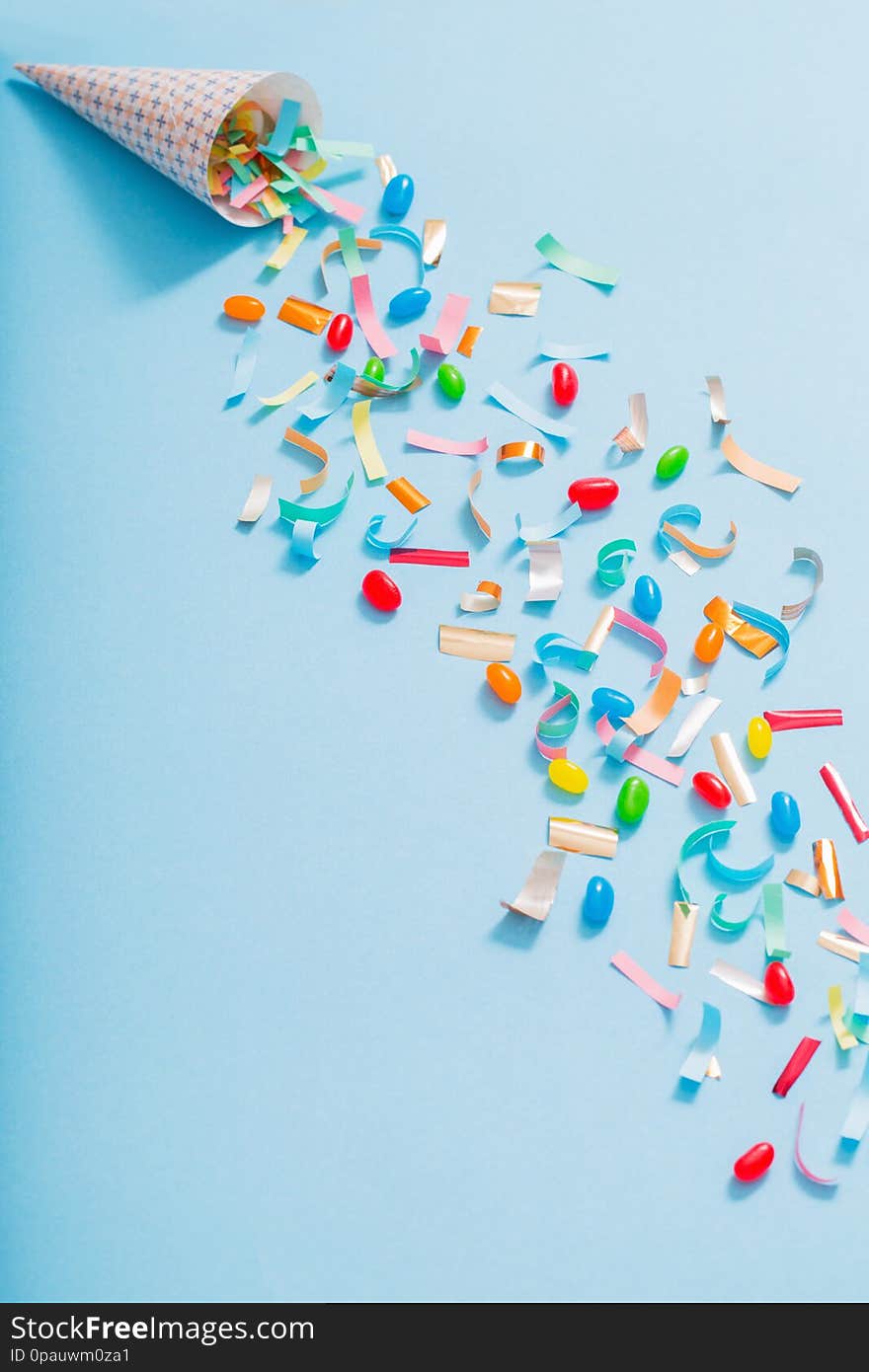 Birthday hat with confetti on blue paper background