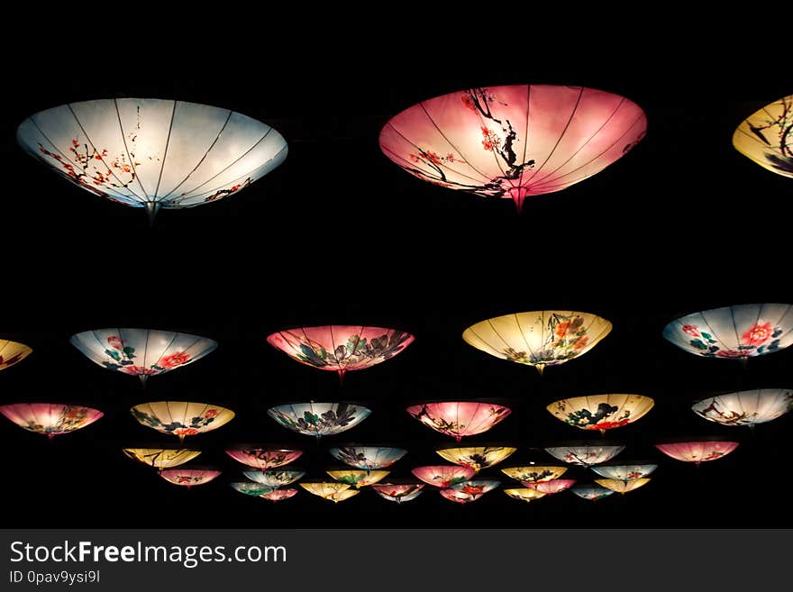Chinese lanterns installation with hanging blue, pink and yellow umbrellas illuminated at night. Chinese lanterns installation with hanging blue, pink and yellow umbrellas illuminated at night
