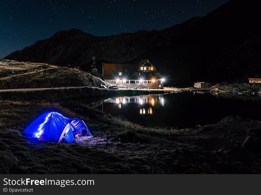 Night mountain landscape with illuminated blue tent. Mountain peaks and the moon. outdoor at Lacul Balea Lake, Transfagarasan