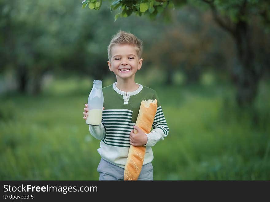 Cute child drinking milk outdoors. Cheerful boy on the picnic.