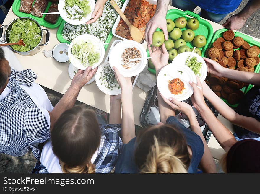 Volunteers serving food for poor people outdoors