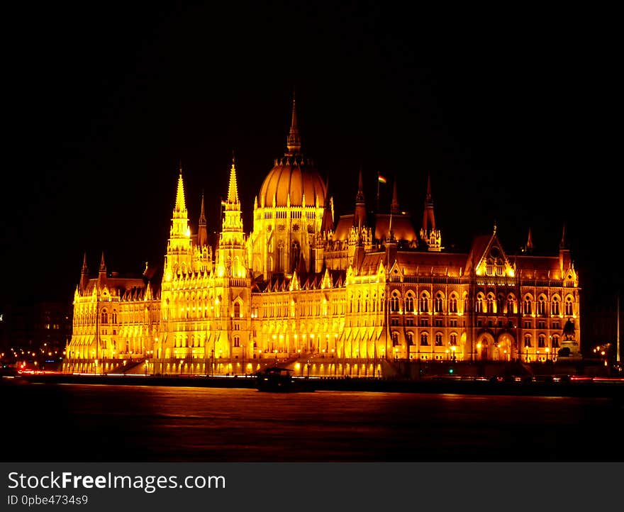 The Hungarian Parliament in Neo Gothic style from across the Danube in panoramic night view with tour boat under black sky. Famous, popular Budapest landmark and tourist attraction. Budapest nightscape. Tourism and travel concept. The Hungarian Parliament in Neo Gothic style from across the Danube in panoramic night view with tour boat under black sky. Famous, popular Budapest landmark and tourist attraction. Budapest nightscape. Tourism and travel concept.