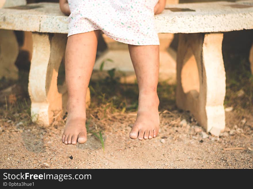 Low section of Asian girl sitting over marble bench at park in twilight