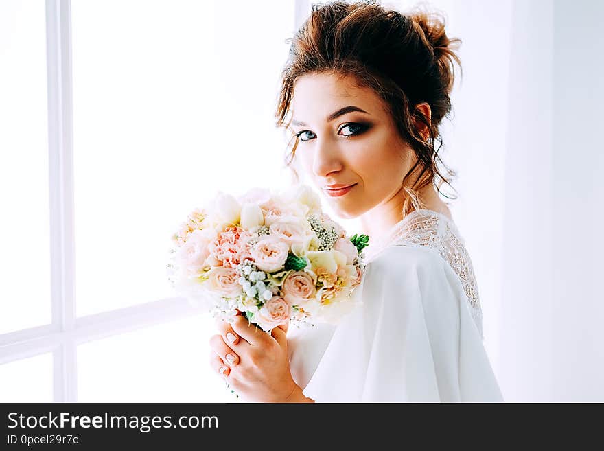 Bridal morning. Beautiful bride getting ready for the wedding ceremony and holding the bouquet. Bridal morning. Beautiful bride getting ready for the wedding ceremony and holding the bouquet