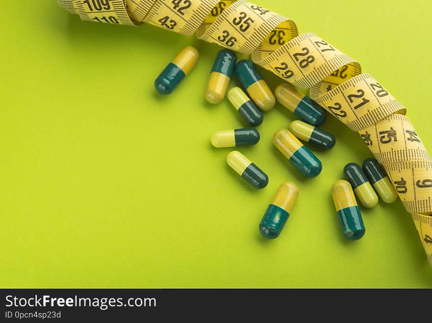 Green and yellow medicine capsule on a bright background. Diet concept and obesity treatment