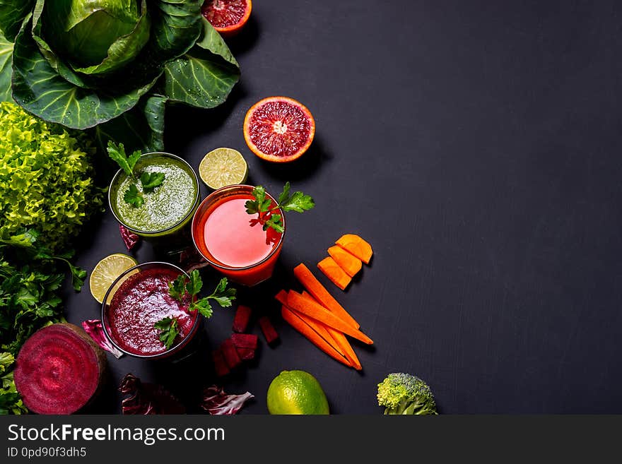 Different healthy vegan drinks with fruits and vegetables on the black wooden background. Flat lay.