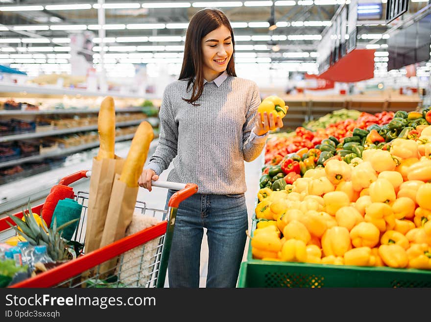 Woman choosing fresh sweet yellow peppers