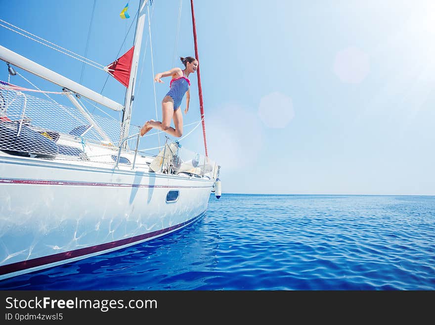 Girl Jump In Sea Of Sailing Yacht On Summer Cruise. Travel Adventure, Yachting With Child On Vacation.