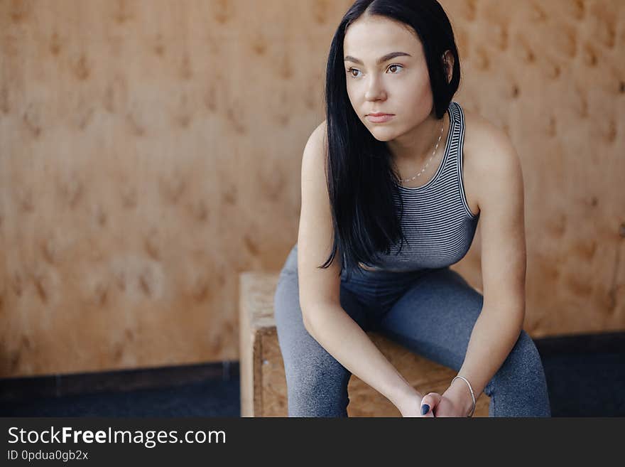 Young girl in sportswear in a gym in a simple background, a theme of fitness, a crossfit and sport, a healthy lifestyle