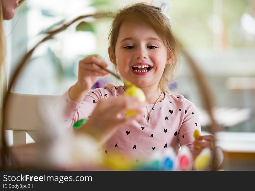 A mother and daughter celebrating Easter, painting eggs with brush