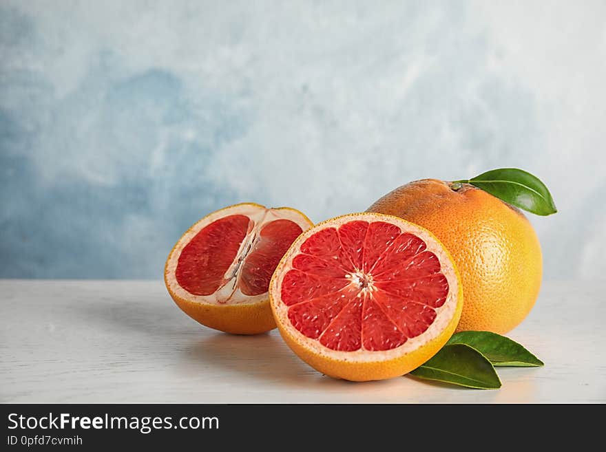 Fresh tasty grapefruits on table against color background. Space for text