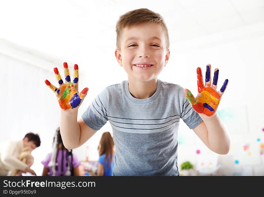 Cute little child showing painted hands at lesson indoors