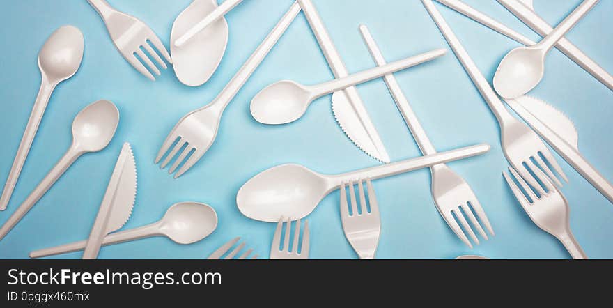 Single-use plastic products: plastic cutlery on bright blue background. Creative minimal concept of life without plastic and enviroment problems. Single-use plastic products: plastic cutlery on bright blue background. Creative minimal concept of life without plastic and enviroment problems