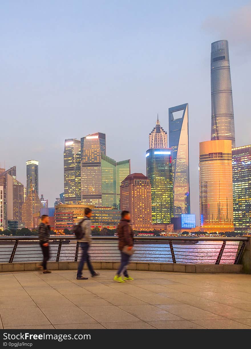 People walking at embankment enjoying illuminated evening Shanghai cityscape view, China