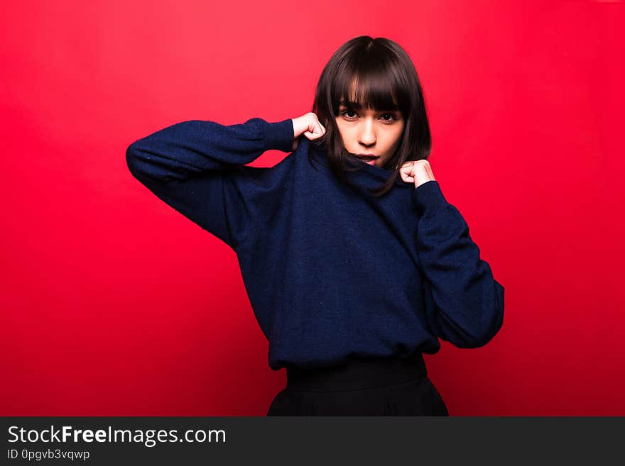 Cheerful beautiful young woman in sweater over red background