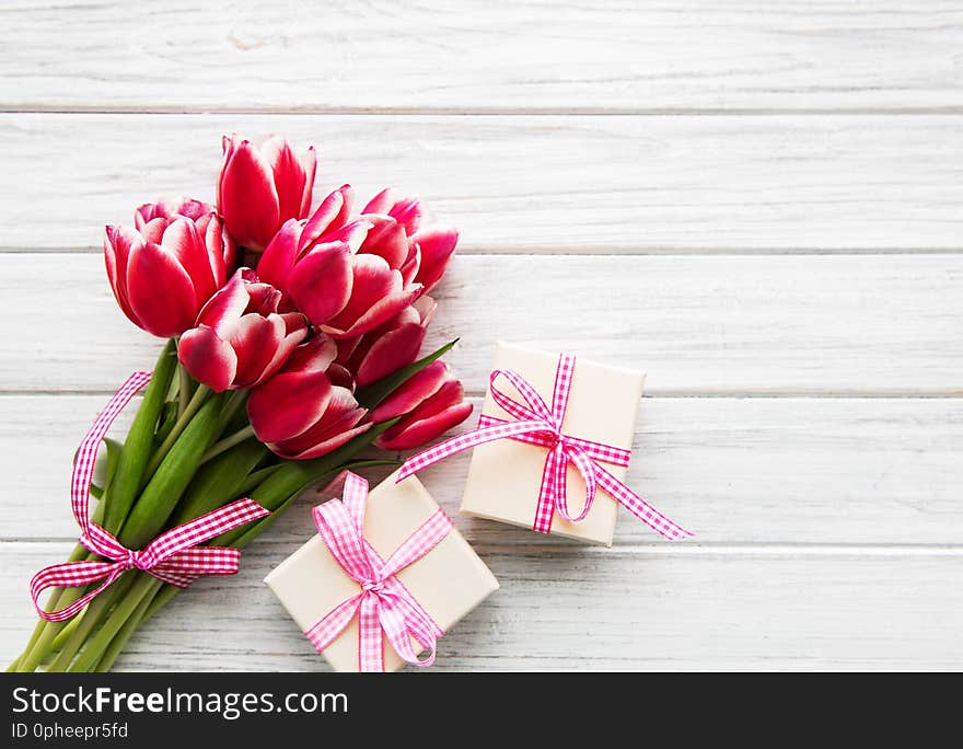 Gift box and tulips bouquet on a old wooden background