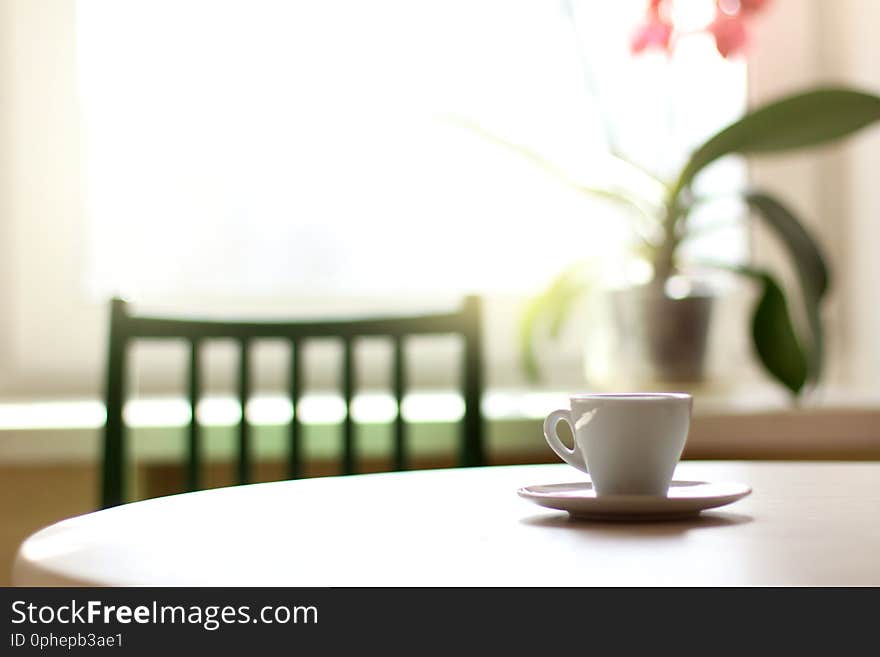 Cup with espresso on the table against the background of the window in the sunny morning. Cup with espresso on the table against the background of the window in the sunny morning