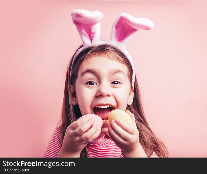 Cute little girl with bunny ears on pink background. Easter child portrait, funny emotions, surprise. Copyspace for text