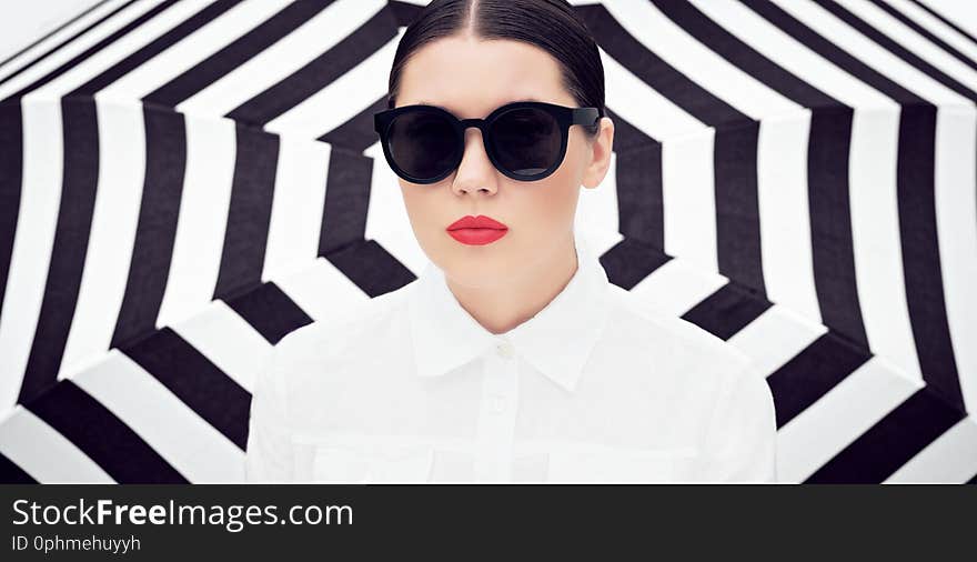 Portrait of a pretty young woman in white chemise and sunglasses with bright painted lips