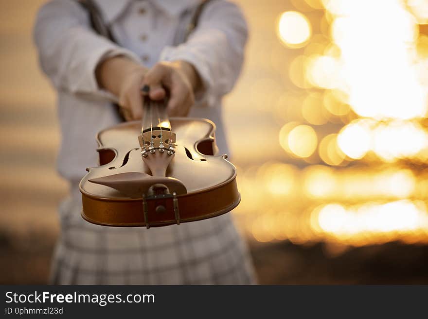 Woman holding violin with sunset background