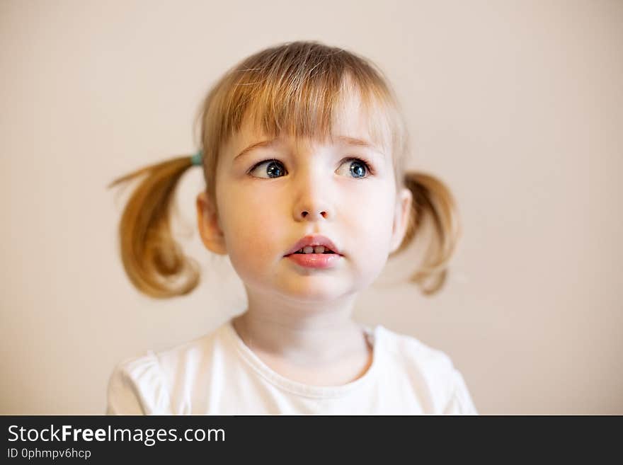 Cute child girl with two pigtails and quiff of blonde hair closeup portrait