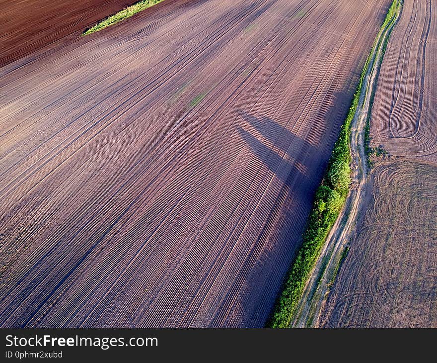 Plowed cultivated spring time agriculture field and bad farm road, aerial view. Plowed cultivated spring time agriculture field and bad farm road, aerial view