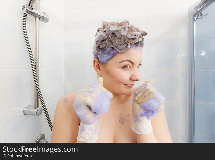 Woman applying coloring shampoo on her hair. Female having purple washing product. Toning blonde color at home. Woman applying coloring shampoo on her hair. Female having purple washing product. Toning blonde color at home