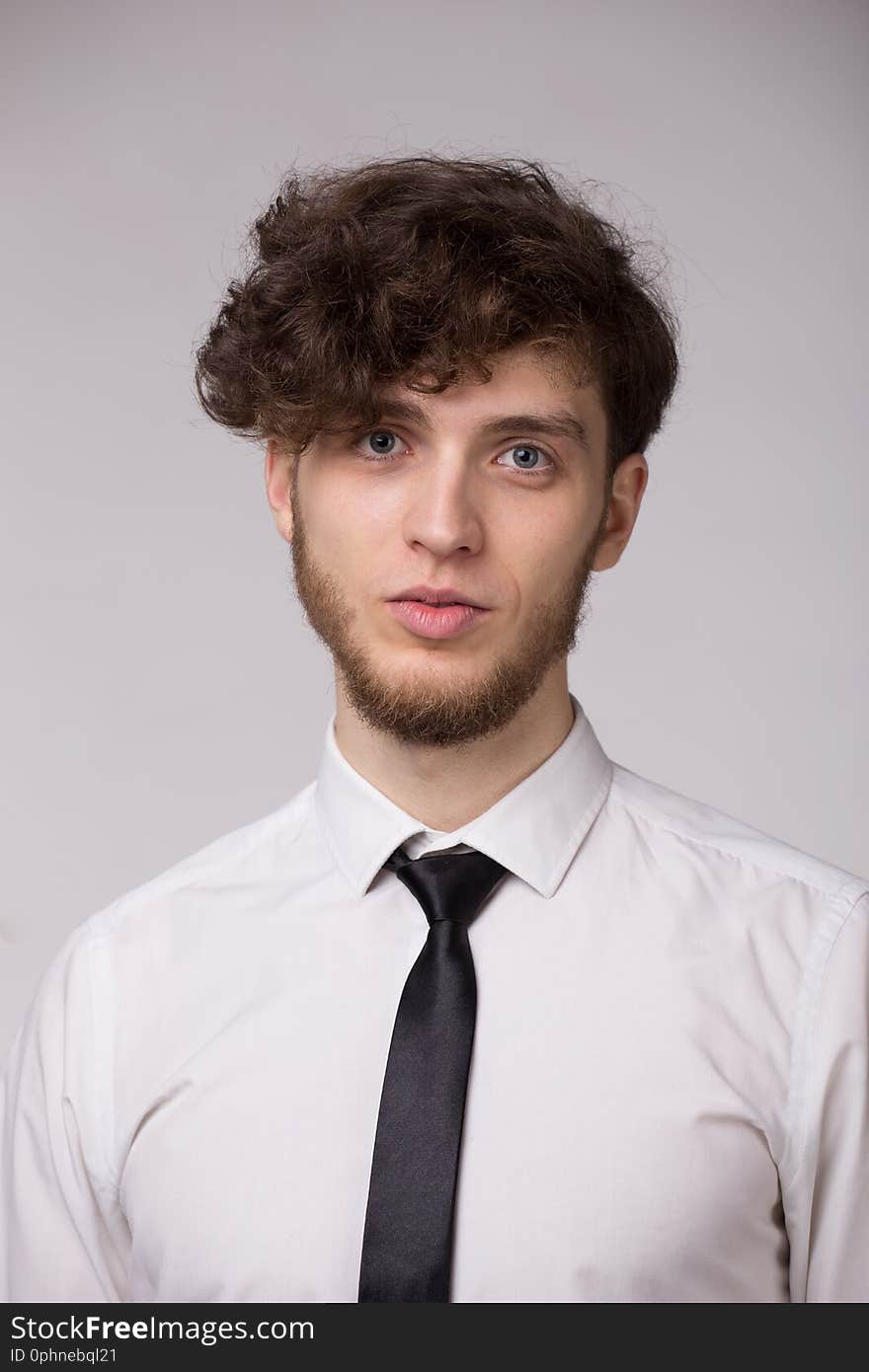 Confident young man in shirt smiling and looking at camera over gray background