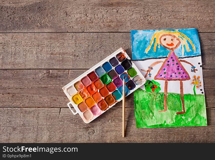 The children is drawing paints on a wooden background