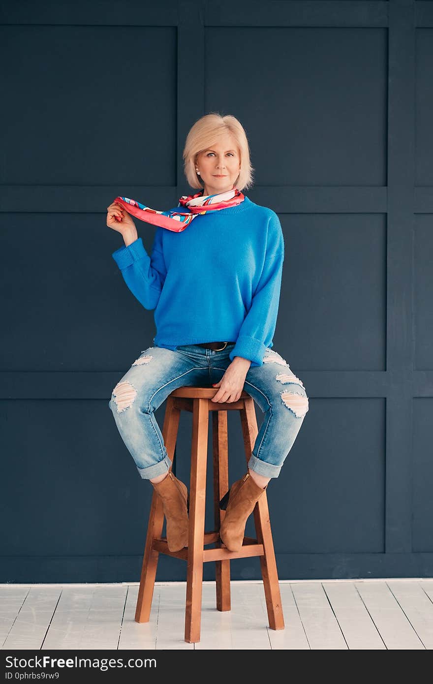 Senior model. Woman beauty. Attractive aged lady sitting on bar stool. Elegance and confidence. Trendy blue outfit. Senior model. Woman beauty. Attractive aged lady sitting on bar stool. Elegance and confidence. Trendy blue outfit.