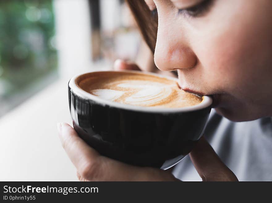 Close up asian woman are drinking Cappuccino coffee in the morning cafe. Close up asian woman are drinking Cappuccino coffee in the morning cafe