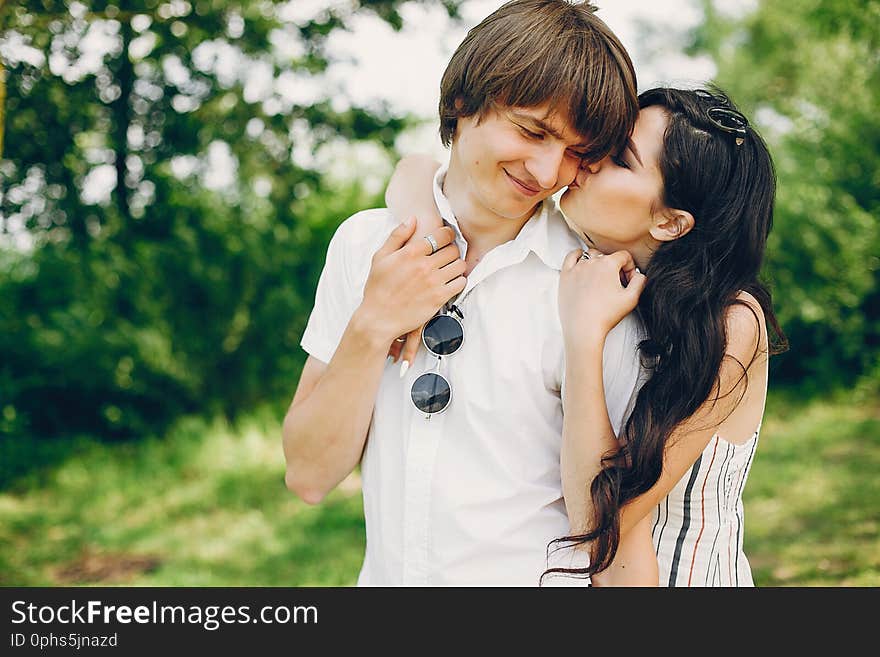 Pretty brunette with her boyfriend. Couple in a summer park. Pretty brunette with her boyfriend. Couple in a summer park.