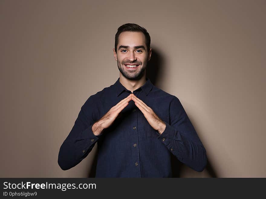 Man showing HOUSE gesture in sign language on color background