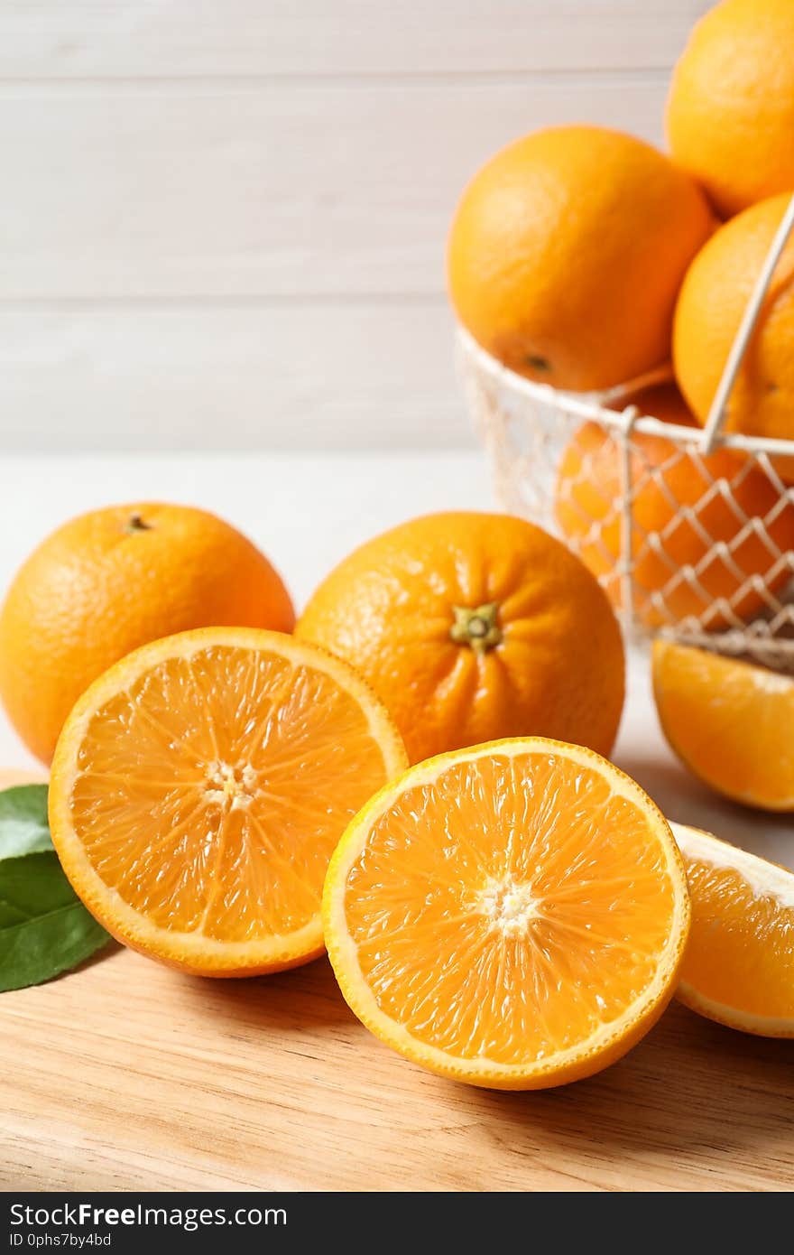 Wooden board with ripe oranges on table