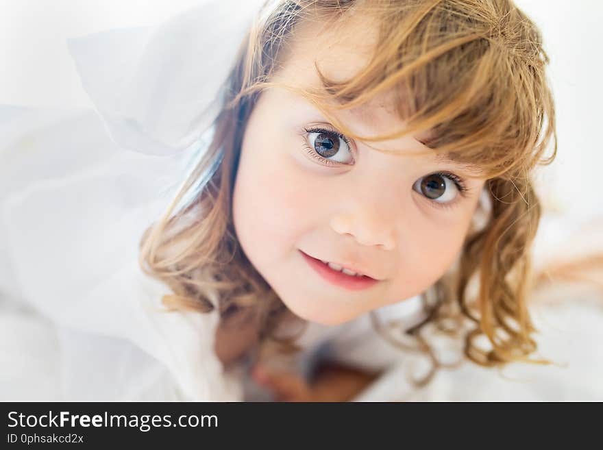 Adorable little girl lying in the bed and smiling in the early morning