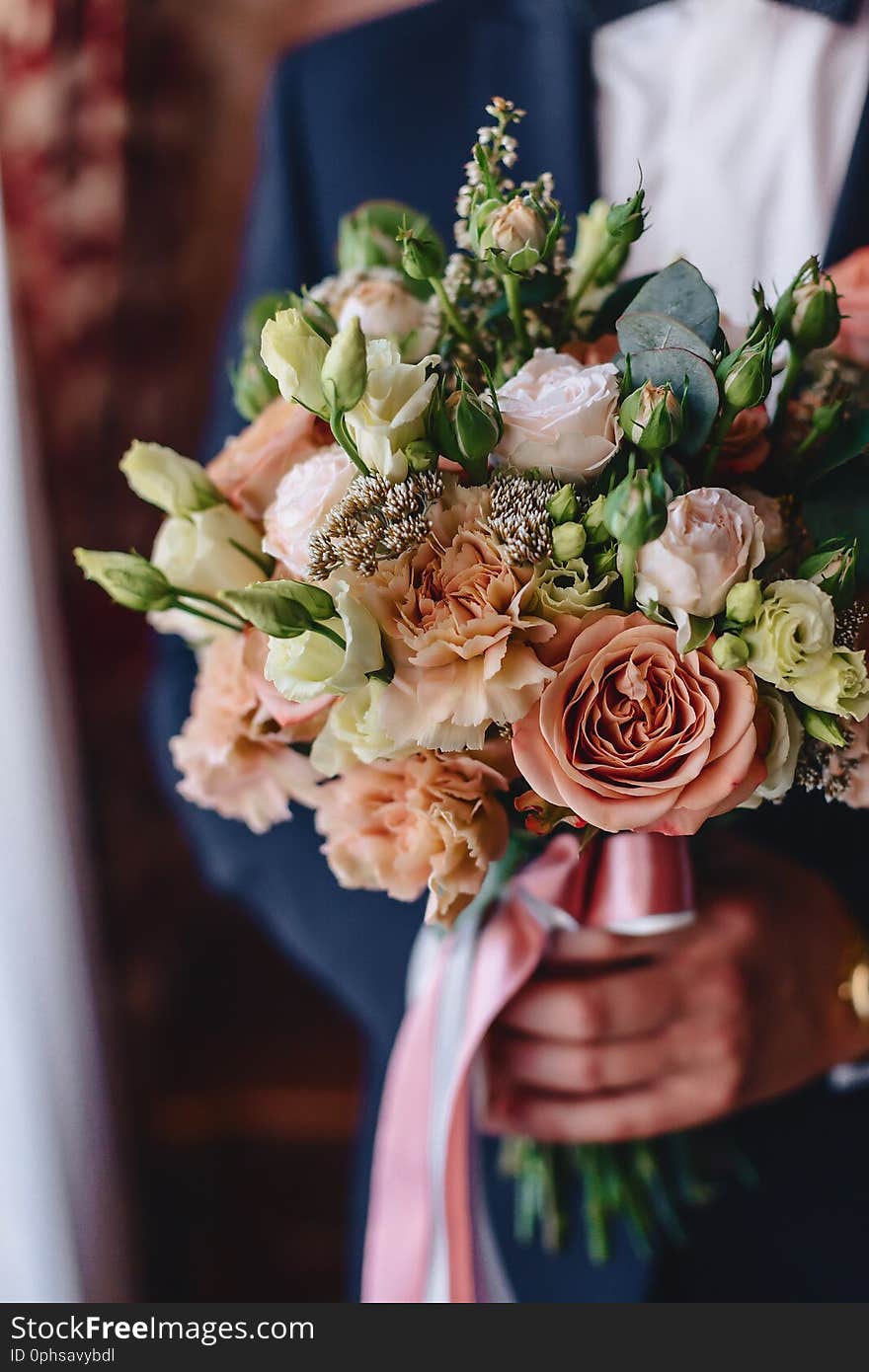 The groom holds elegant wedding bouquet in his hands