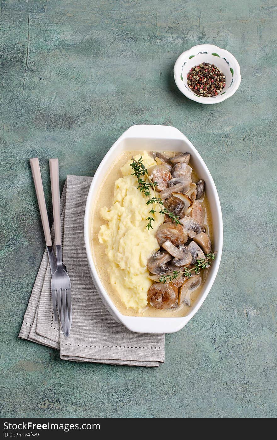 Mashed potatoes and slices of mushrooms with sausages in sauce. Selective focus