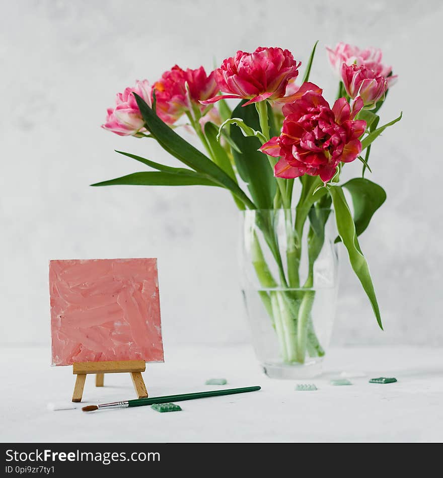 Vase with tulip flowers ,paintbrush with color on a canvas painting and mosaic on gray backround. Art concept. Color of the year 2019 Living Coral. Still life