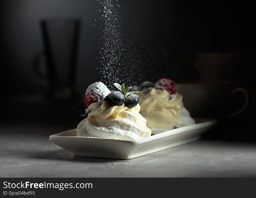 Dessert Pavlova with blueberries and raspberries sprinkled with powdered sugar. Dessert Pavlova with blueberries and raspberries sprinkled with powdered sugar