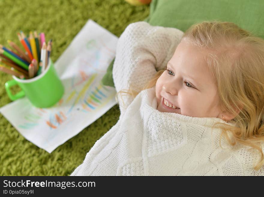 Cute little girl lying on green carpet at home