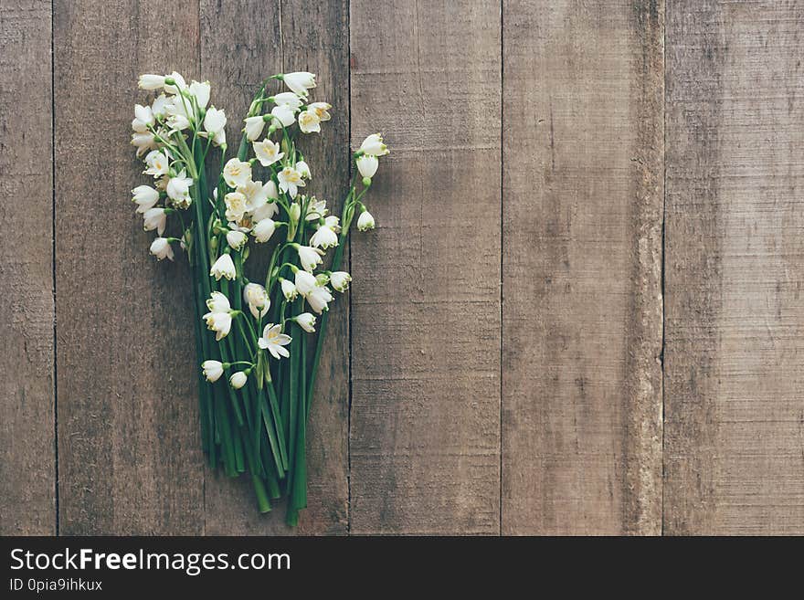 Bouquet of snowdrops primroses on a wooden background. Postcard in a rustic style. Invitation and congratulations on spring holidays