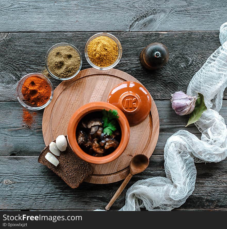 Meat in a saucepan on a wooden stand. Stands on a table with spices