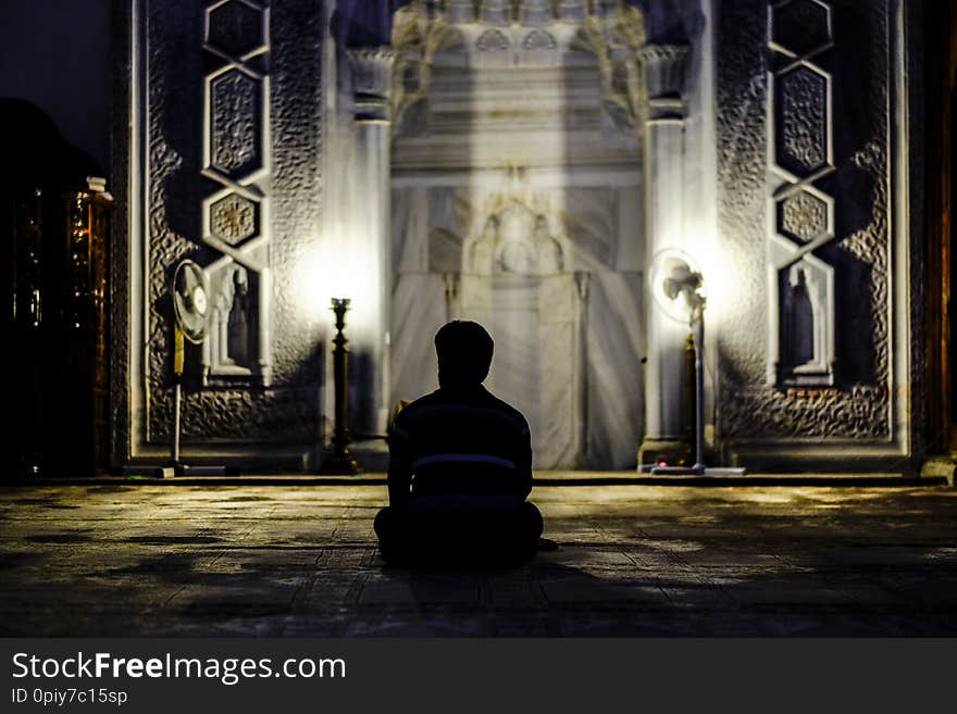 Man praying in mosque with his back to the camera
