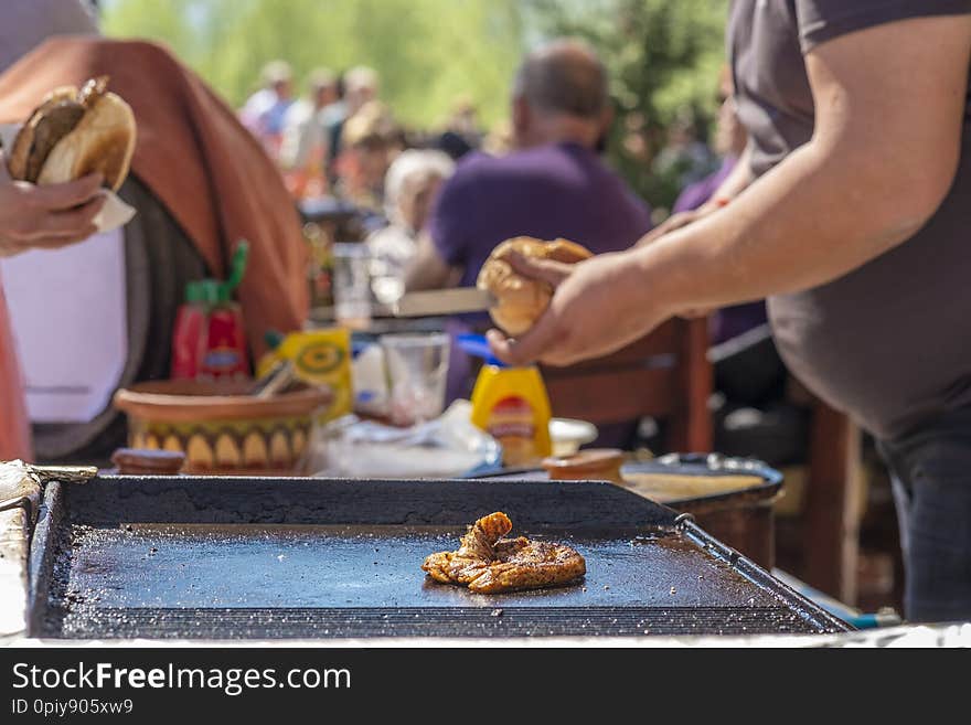 A fat young guy makes hamburgers with fried beef succulent appetizing cutlets and sells them to the guests of the festival. A fat young guy makes hamburgers with fried beef succulent appetizing cutlets and sells them to the guests of the festival