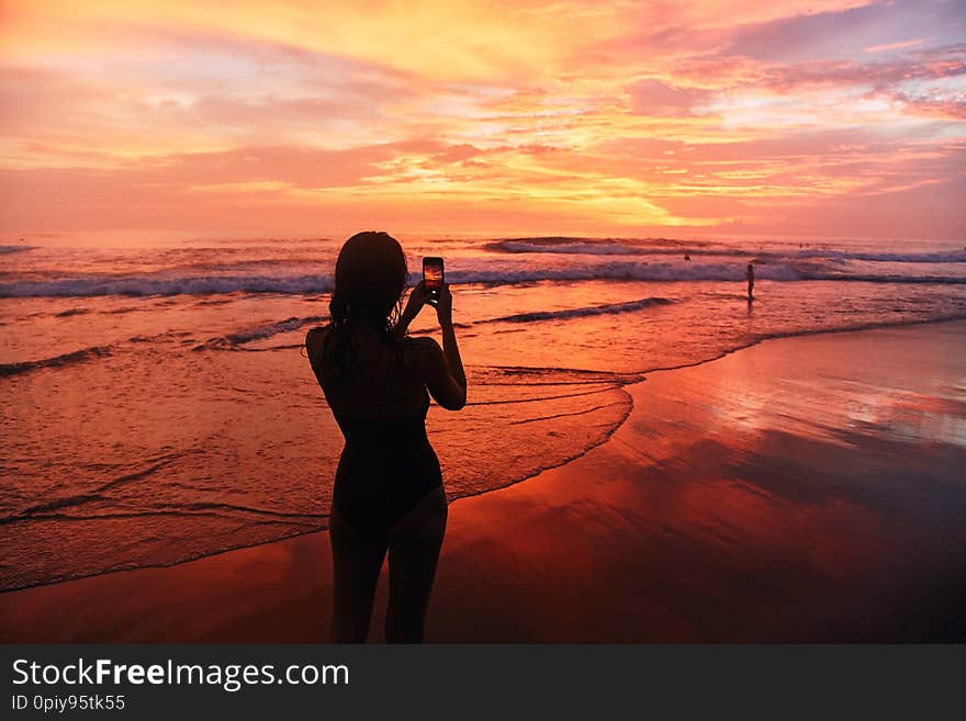 Girl takes a sunset photo on the phone